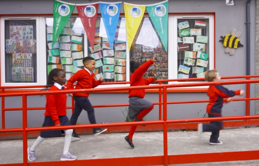 Four school kids jumping in front of school building